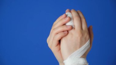 Parmakta yaralanma, kolda mavi bir arka planda bandaj. Kırık, kemikte çatlak, parmak ekleminde travma.