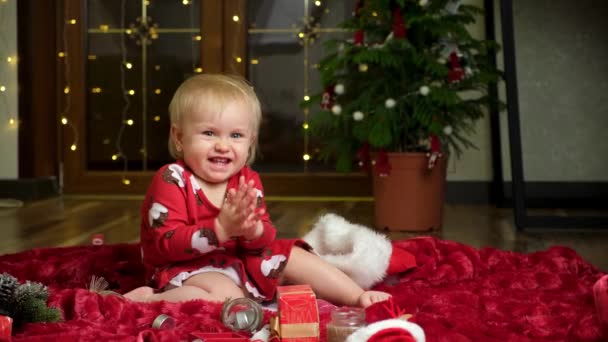 Ένα Γλυκό Κορίτσι Ενάμισι Έτους Χειροκροτεί Γιρλάντες Και Ένα Χριστουγεννιάτικο — Αρχείο Βίντεο