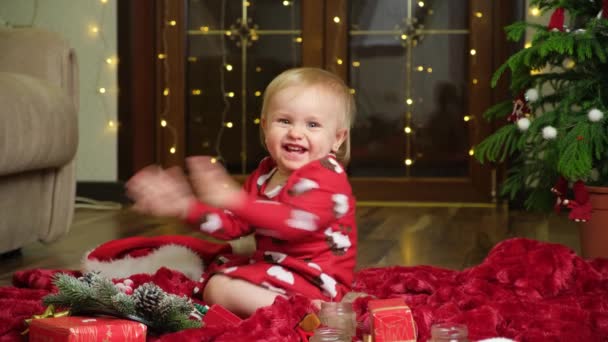 Ένα Γλυκό Κορίτσι Ενάμισι Έτους Χειροκροτεί Γιρλάντες Και Ένα Χριστουγεννιάτικο — Αρχείο Βίντεο