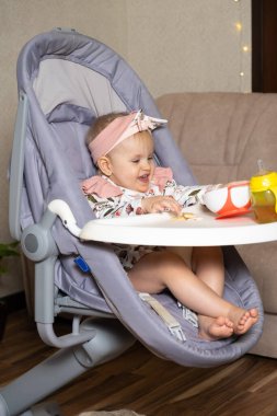 Bir yaşındaki tatlı bir kız tabaktan kurabiye döküyor. Çocuklar için tamamlayıcı gıdalar, kendini besleme, yemeklerde şeker