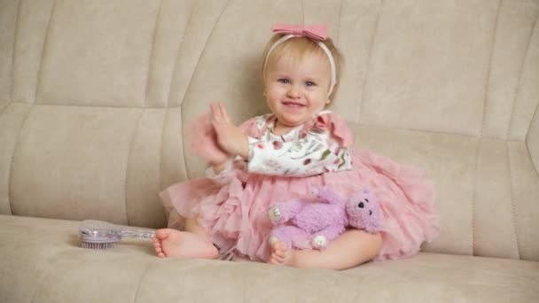 Милая Однолетняя Блондинка Розовом Платье Сидит Диване Расчёской Медвежьей Игрушкой — стоковое видео