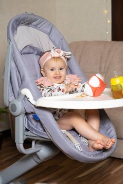 Bir yaşındaki tatlı bir kız tabaktan kurabiye döküyor. Çocuklar için tamamlayıcı gıdalar, kendini besleme, yemeklerde şeker