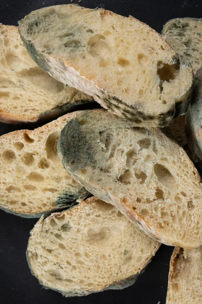 Mold on bread on a black background close-up. The danger of mold, stale products
