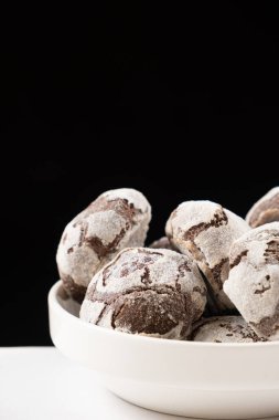 Chocolate chip cookies with cocoa and powdered sugar on a plate on a black background