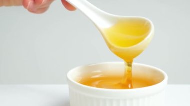 Liquid bee honey in a spoon, showing linden fresh honey on a white background