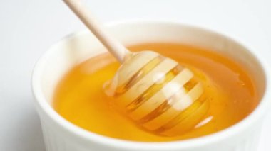 Liquid bee honey in a wooden spoon, showing linden fresh honey on a white background