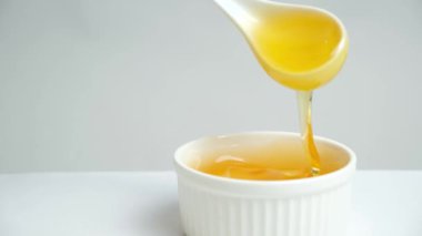 Liquid bee honey in a spoon, showing linden fresh honey on a white background