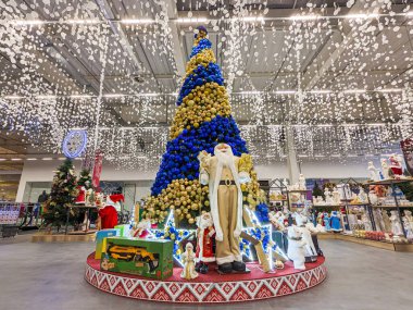 A large figure of Santa near a Christmas tree in a supermarket