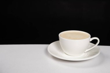 Coffee with milk cream, cappuccino in a white ceramic cup on a black white background, copy the place for the text.