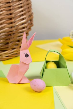 An easter bunny figurine made of paper, origami, and a basket with eggs, happy easter
