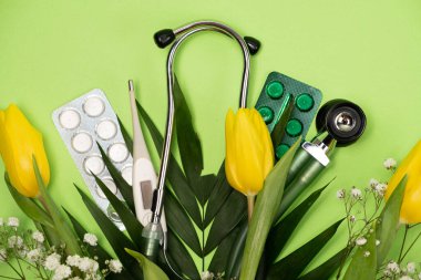 Bouquet of flowers and stethoscope on a green background, happy doctors day, nurses week and other medical holidays