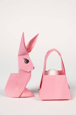 Easter origami bunny and a basket of eggs on a white background. Paper crafts, do it yourself.