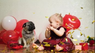 A little girl and a pug are showered with sequins of confetti - children, pets and Valentines Day.