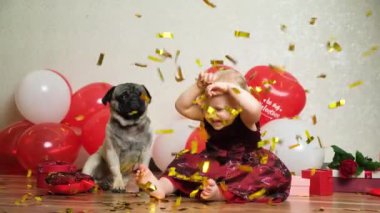 A little girl and a pug are showered with sequins of confetti - children, pets and Valentines Day.