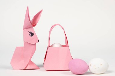 Easter origami bunny and a basket of eggs on a white background. Paper crafts, do it yourself.