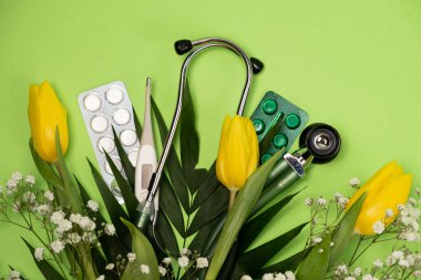 Bouquet of flowers and stethoscope on a green background, happy doctors day, nurses week and other medical holidays