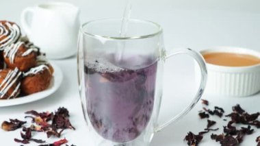 The process of making red hibiscus tea from sudanese rose flowers in a glass cup.