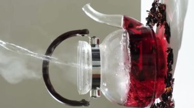 The process of making red hibiscus tea from sudanese rose flowers in a glass teapot.