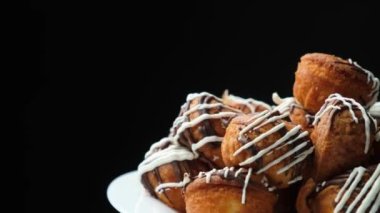 Small cupcakes with cocoa and white and milk chocolate with cream on a black background close-up.