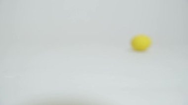 Easter chocolate eggs quickly fall from top to bottom and roll across a white background