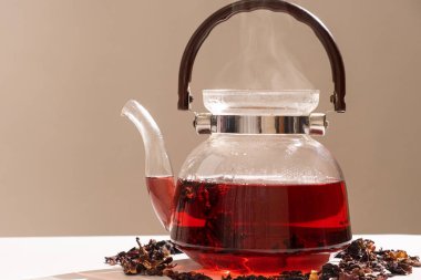 Red hibiscus tea from the petals of a Sudanese rose in a glass teapot, copy the place for the text.