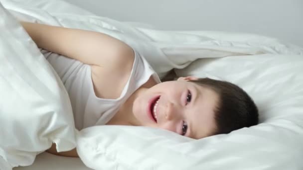 Ein Jähriger Junge Liegt Auf Dem Bett Und Lugt Lachend — Stockvideo