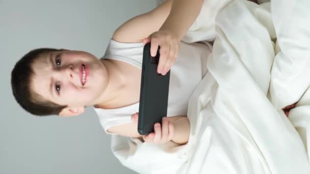 Preschool Boy Watches Cartoons Plays Games Smartphone While Sitting Bed — Stok video