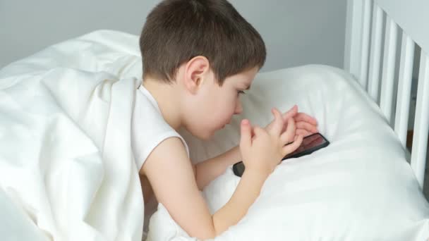 Yaşında Bir Çocuk Yatakta Yatarken Telefonuyla Oyun Oynuyor Bir Çocukta — Stok video