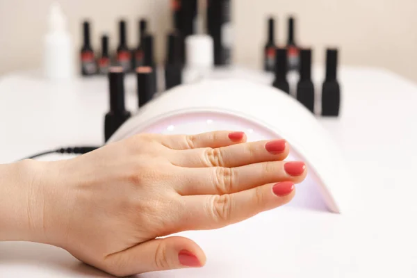Led uv lamp for drying gel polish and hand with pink coating. Manicure, spa salon.