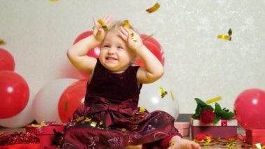 Valentines Day and children - a sweet one-and-a-half-year-old girl is showered with festive sparkles of confetti