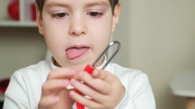 A focused 5 or 6 year old boy licks his lips, sticks out his tongue trying to open the lock