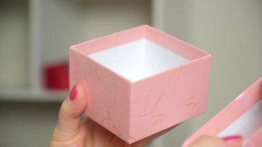 Pink box with a gift in womens hands. Concept of gifts, holidays, valentines day, mothers day, wedding anniversary, birthday.