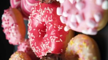 Donuts with red, pink and chocolate icing and marshmallows spin the view from above.