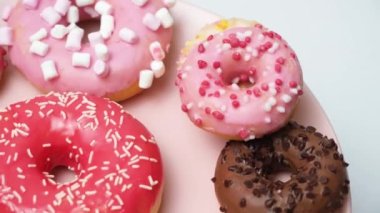 Donuts with red, pink and chocolate icing and marshmallows spin the view from above.