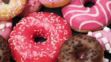 Donuts with red, pink and chocolate icing and marshmallows spin the view from above.