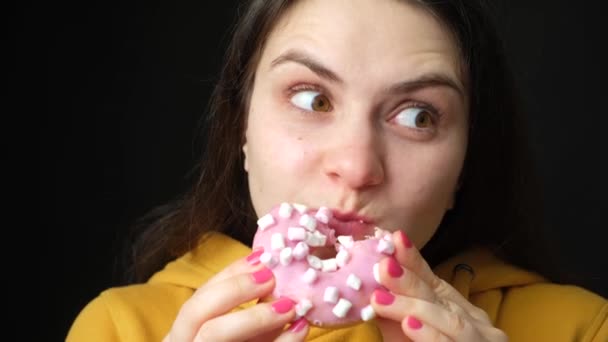 女性のグルトンはドーナツを食べ 何度も噛み回して周りを見回します Gluttony 余分な体重 体重減少 — ストック動画