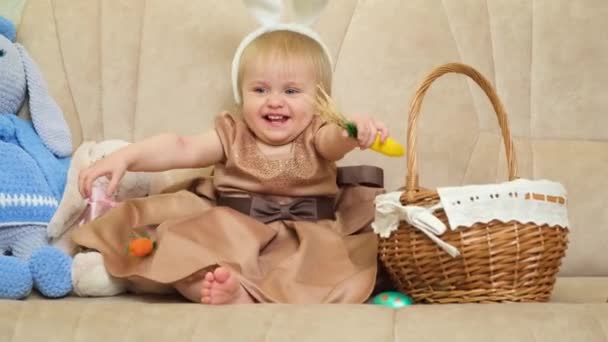 Eineinhalbjähriges Blondes Mädchen Spielt Mit Karotten Entfernt Hasenohren Vom Kopf — Stockvideo