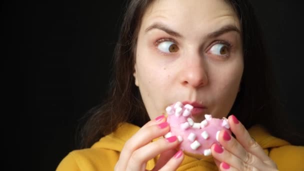 Een Vrouwtje Glutton Eet Een Donut Bijt Vaak Kijkt Zich — Stockvideo