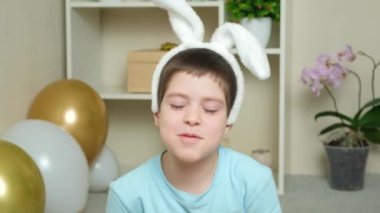 Anaokulundan bir Paskalya çocuğu kafasında tavşan kulağı ve havuçla oynar.