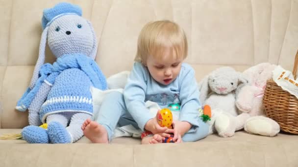 Wielkanocne Dziecko Półtoraletnia Blondynka Bawi Się Malowanymi Jajkami Kanapie — Wideo stockowe