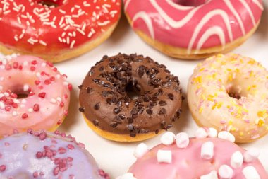 Beyaz arka planda birçok farklı donut, farklı boyutlarda pembe, beyaz ve çikolatalı çörekler..