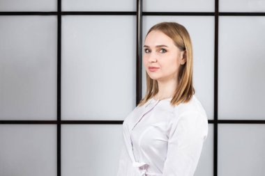 Siyah beyaz arka planda beyaz üniformalı sarışın bir doktorun portresi.