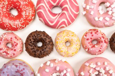 Beyaz arka planda birçok farklı donut, farklı boyutlarda pembe, beyaz ve çikolatalı çörekler..