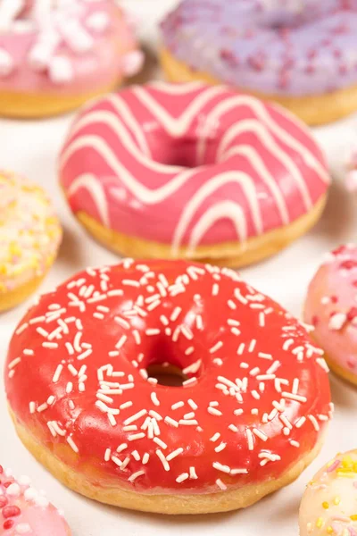 Donuts with red and pink glaze, top view. Lots of donuts, sweet and delicious food.