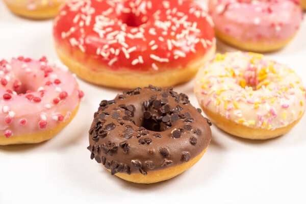 Many different donuts on a white background top view, pink, white and chocolate donuts of different sizes.