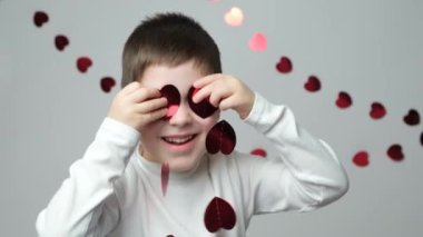 Sevimli küçük anaokulu çocuğu sevgililer gününde kalp şeklinde bir çelenkle oynuyor..