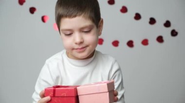 5 yaşında tatlı bir çocuk, içinde hediye olan kırmızı bir kutu veriyor. Anneler Günü, Babalar Günü ya da Sevgililer Günü.