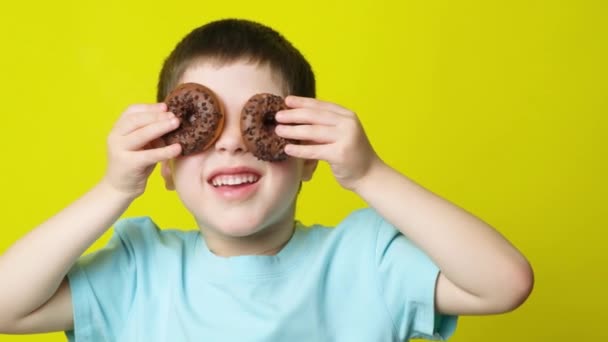 Хлопчик Дошкільного Віку Розважається Пончиками Ставить Біля Очей Окуляри — стокове відео