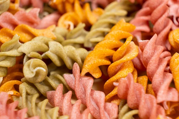 Rice vegetable pasta in the form of spirals, top view. Healthy rice pasta with tomatoes, selenera, carrots and beets.