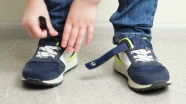 Anaokulu çocuğu, spor ayakkabılarına cırt cırt bağlıyor, bağımsız çocuk kıyafeti giyiyor..